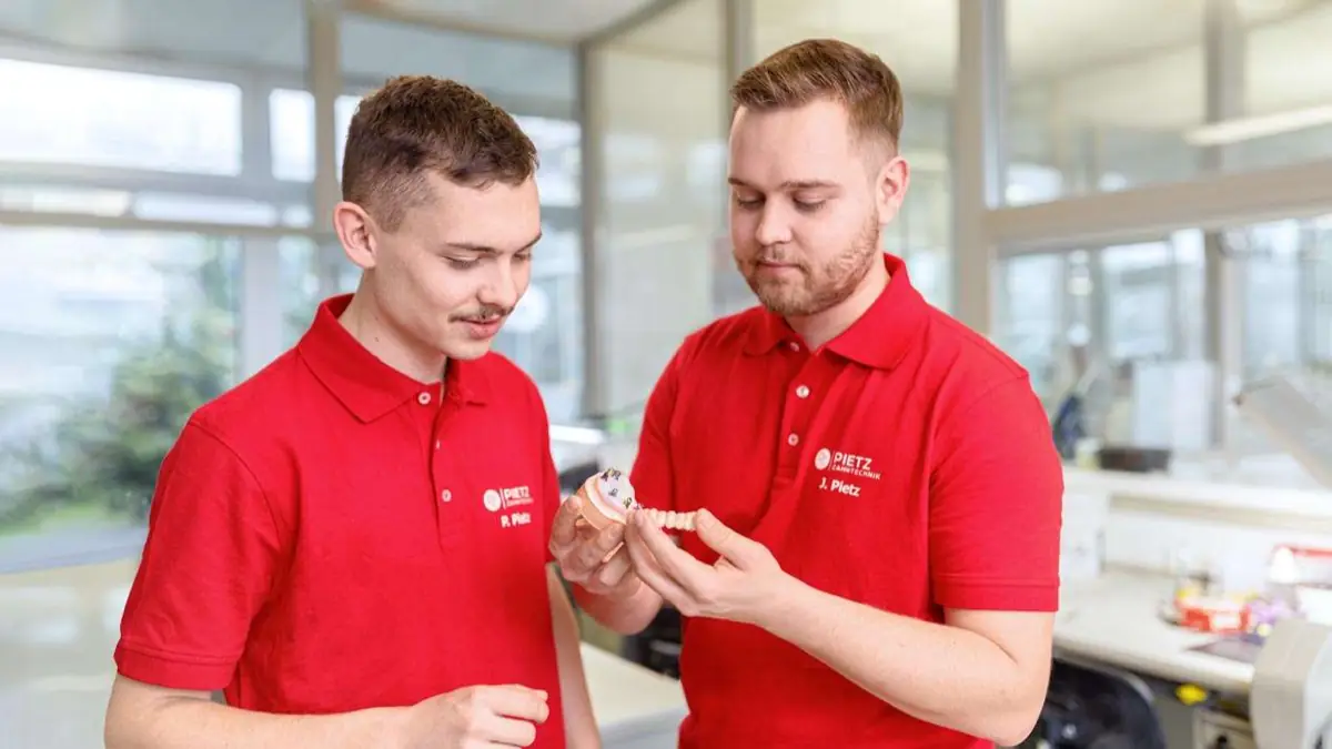 Zahntechnikerin arbeitet an einem Modell am Laborarbeitsplatz